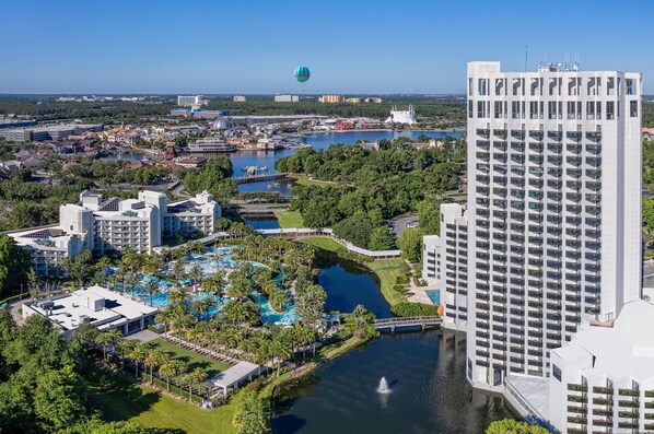 A resort with multiple swimming pools, a large water body, and a high-rise building. - Hilton Orlando Buena Vista Palace - Disney Springs® Area (Lake Buena Vista)
