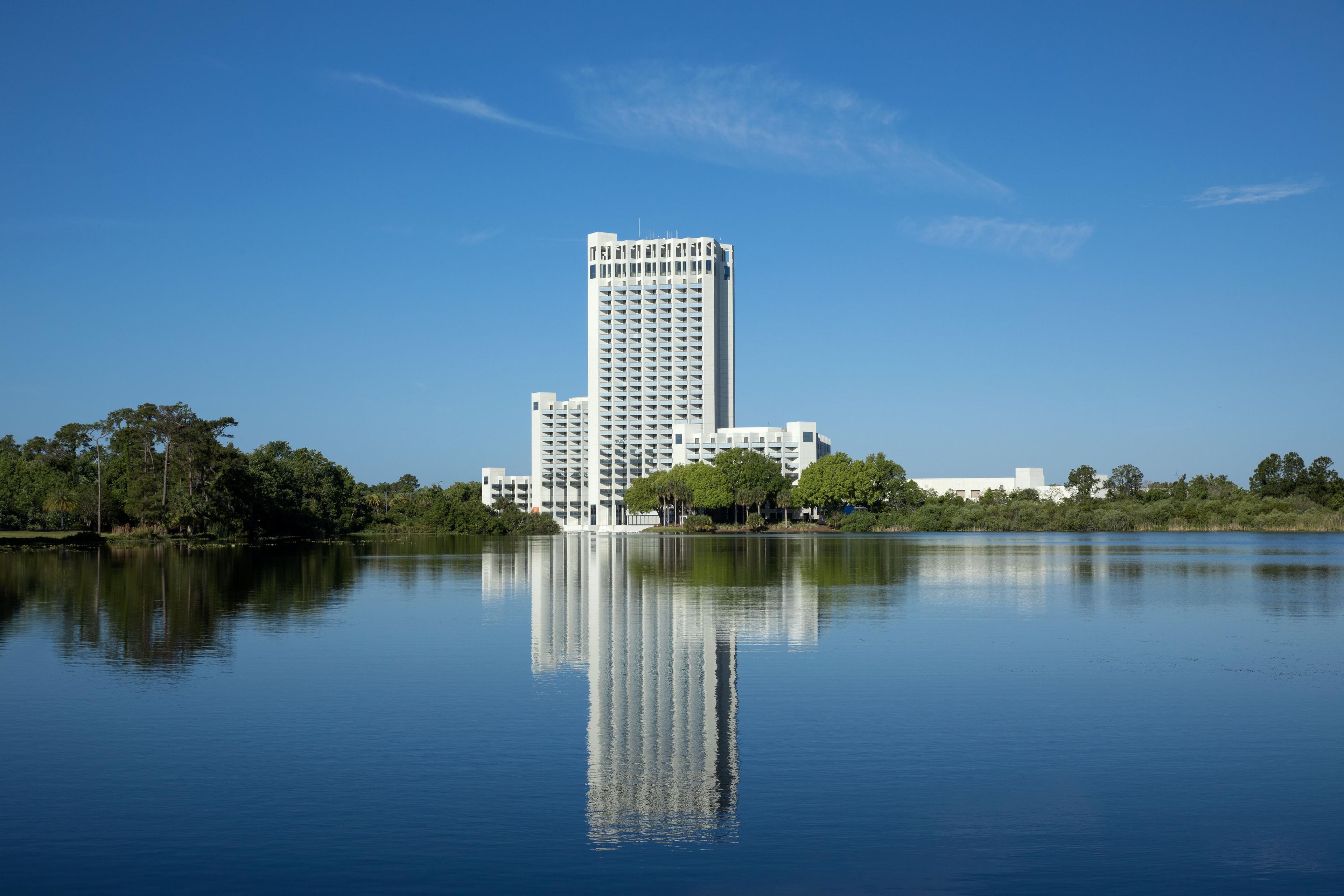 A high-rise building with multiple floors, surrounded by a body of water reflecting its structure.