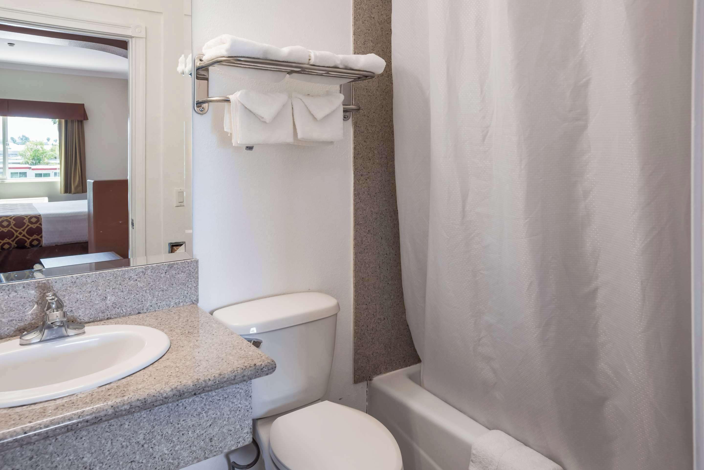 A bathroom with a sink, toilet, and bathtub. There is a towel rack with towels above the toilet.