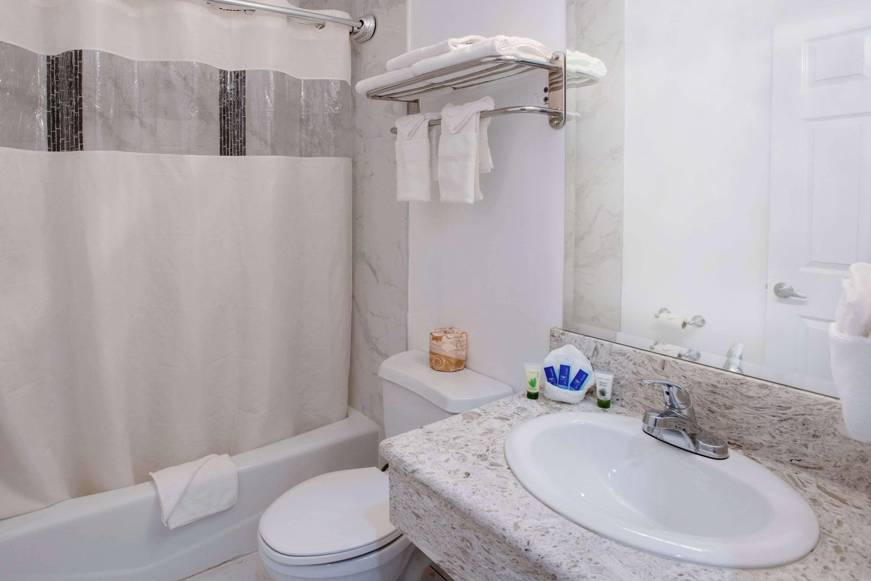 A bathroom with a bathtub, toilet, sink, and a towel rack.