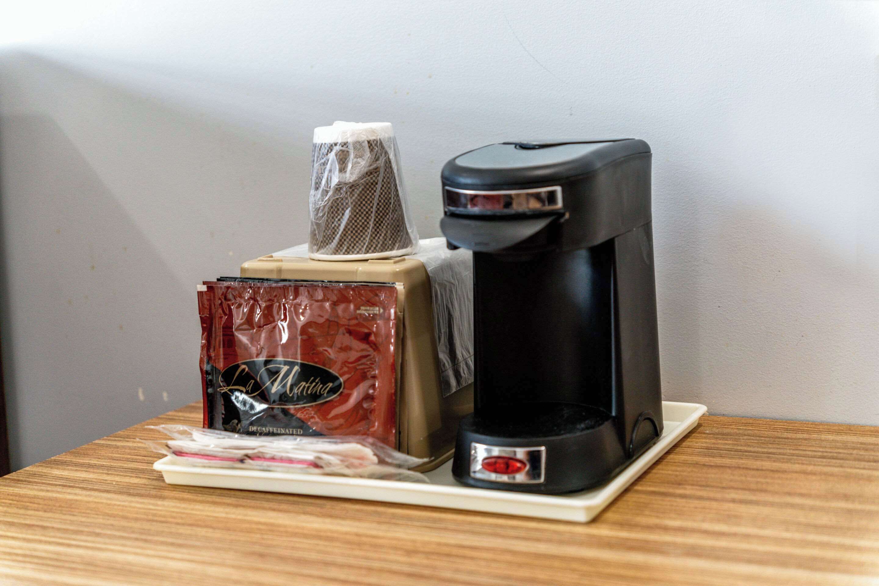 Une machine à café, une boîte de café décaféiné de la marque La Meringue et un filtre en tissu sur une table en bois.