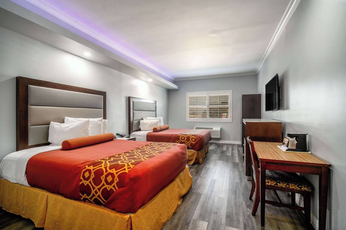 Een hotelkamer met twee bedden, een bureau en een televisie.