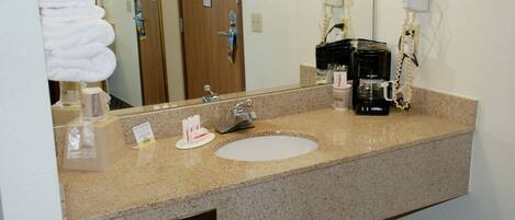 A hotel bathroom with a sink, towel dispenser, and hair dryer.