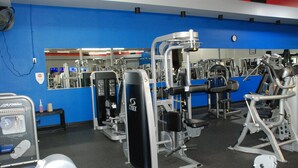 A gym with various exercise machines, a mirror, and a blue wall.