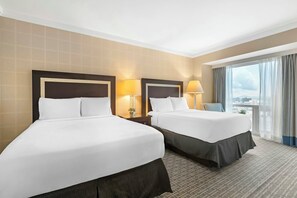Une chambre d’hôtel avec deux lits, une grande fenêtre avec des rideaux et une vue sur la ville.