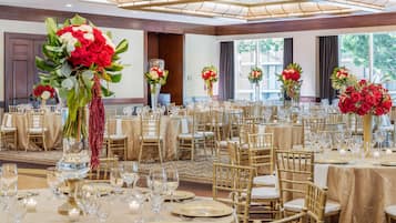 A banquet hall with round tables set for dining, each with gold tablecloths and white chairs.