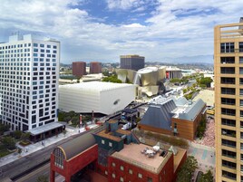 A modern urban area with a mix of architectural styles, including a prominent white building with a unique facade and a red brick building with a curved roof.