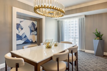 A hotel room with a sofa, two armchairs, a coffee table, a TV, and a cabinet. at Omni Los Angeles Hotel at California Plaza
