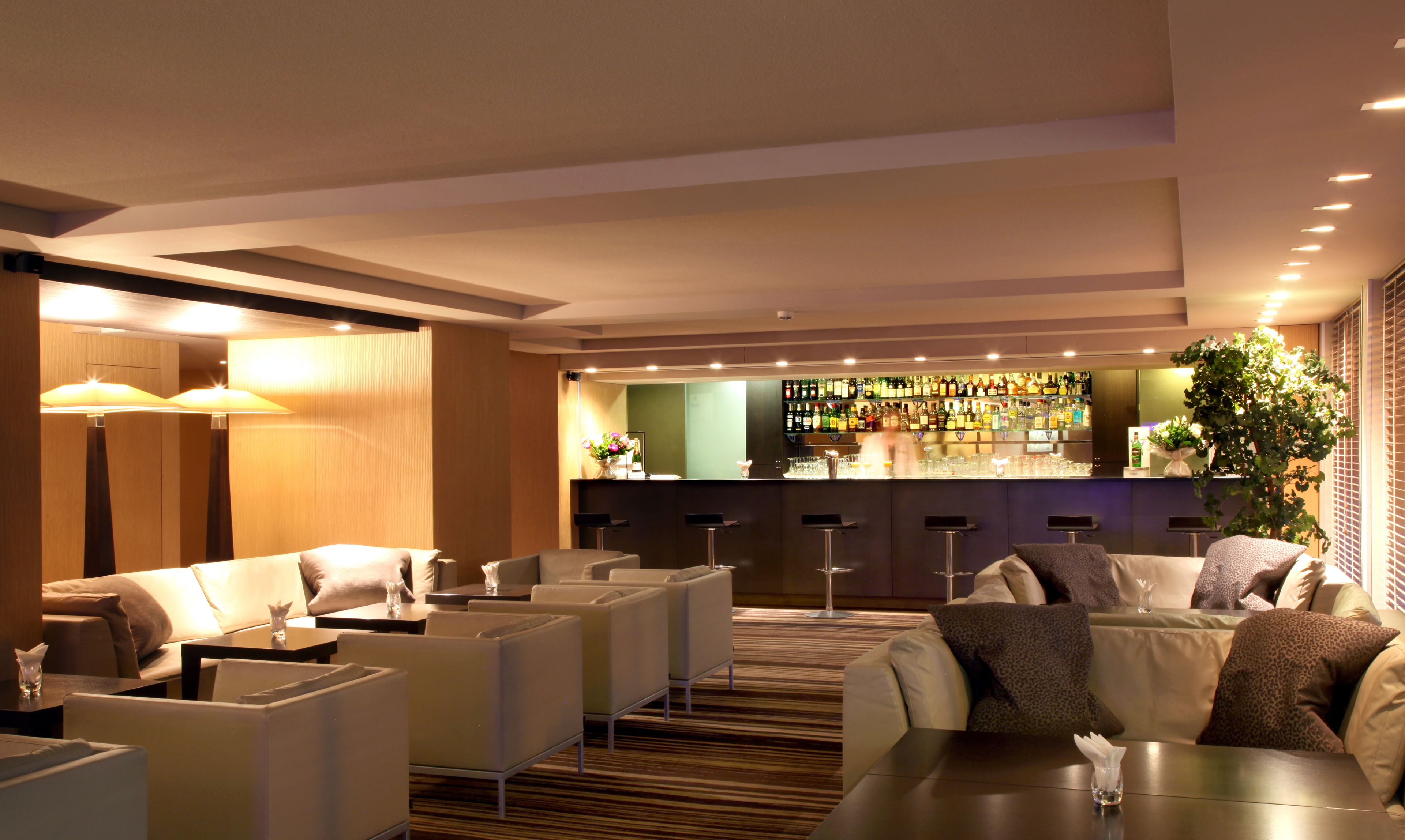 Un hall de hotel con zonas de estar, un bar y una recepción.