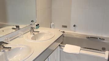 A bathroom with two sinks, a mirror, and a bathtub.