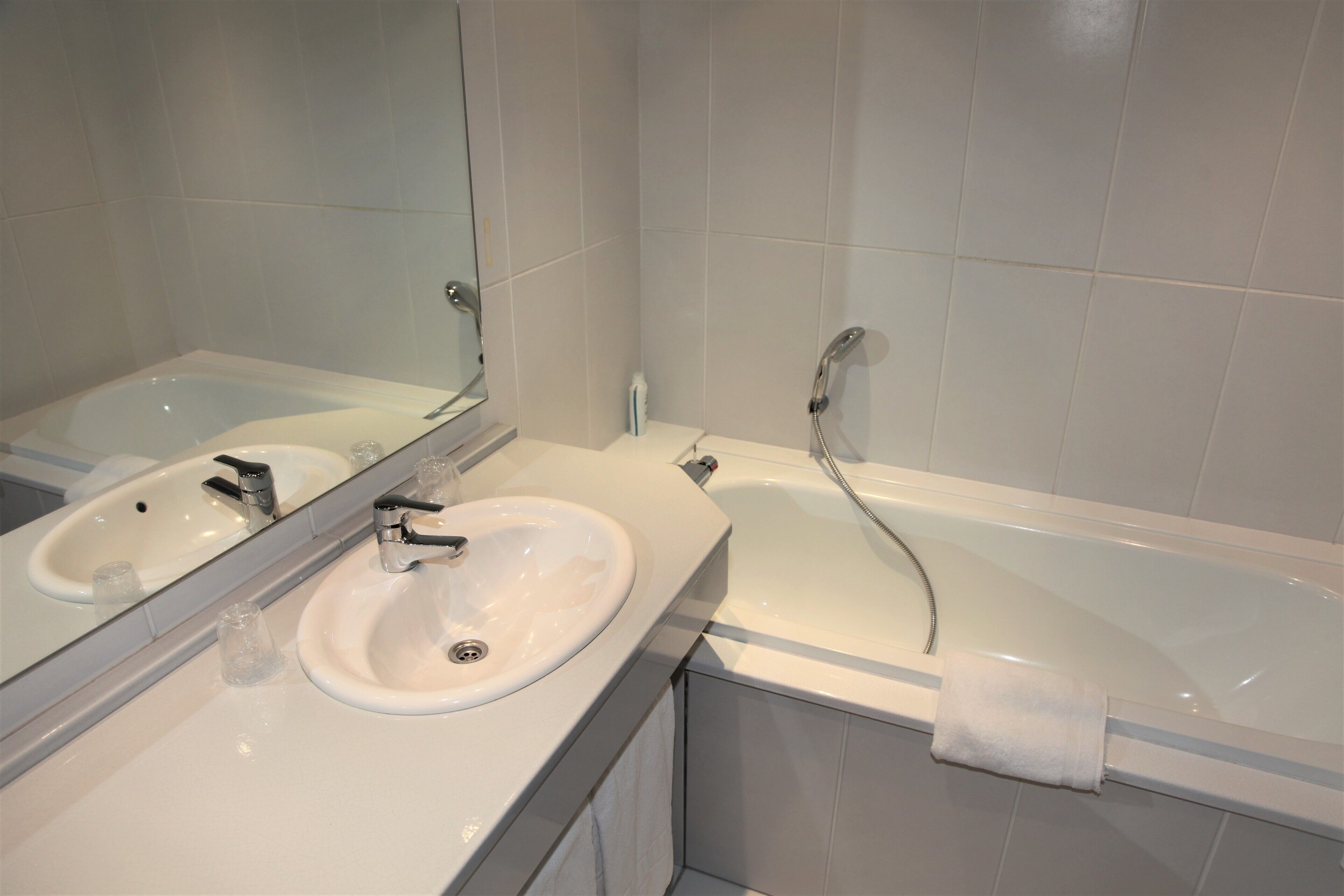 Een badkamer met een wastafel, een bad en een grote spiegel.