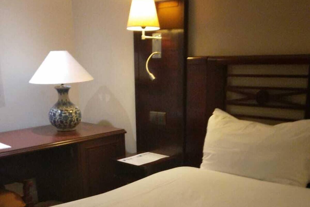 Une chambre d’hôtel avec un lit bien fait, une table de chevet avec une lampe et un luminaire fixé au mur.