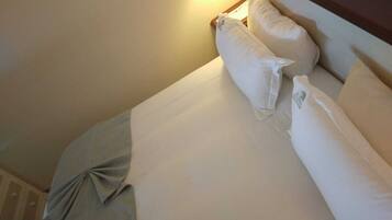 Habitación de hotel con una cama bien hecha, almohadas y una manta.