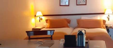 A hotel room with a bed, bedside tables, a desk, and a sofa.
