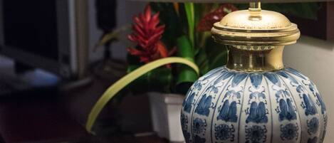 Una lámpara de mesa con base estampada en azul y blanco y pantalla color beige, sobre un escritorio de madera.