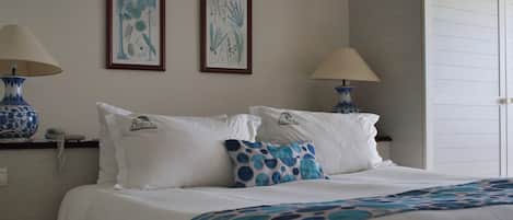 Una camera d'albergo con un letto, due lampade a parete, un telefono e due stampe botaniche incorniciate.