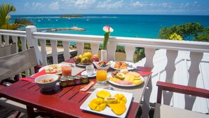 A table set with breakfast items and a view of the ocean.
