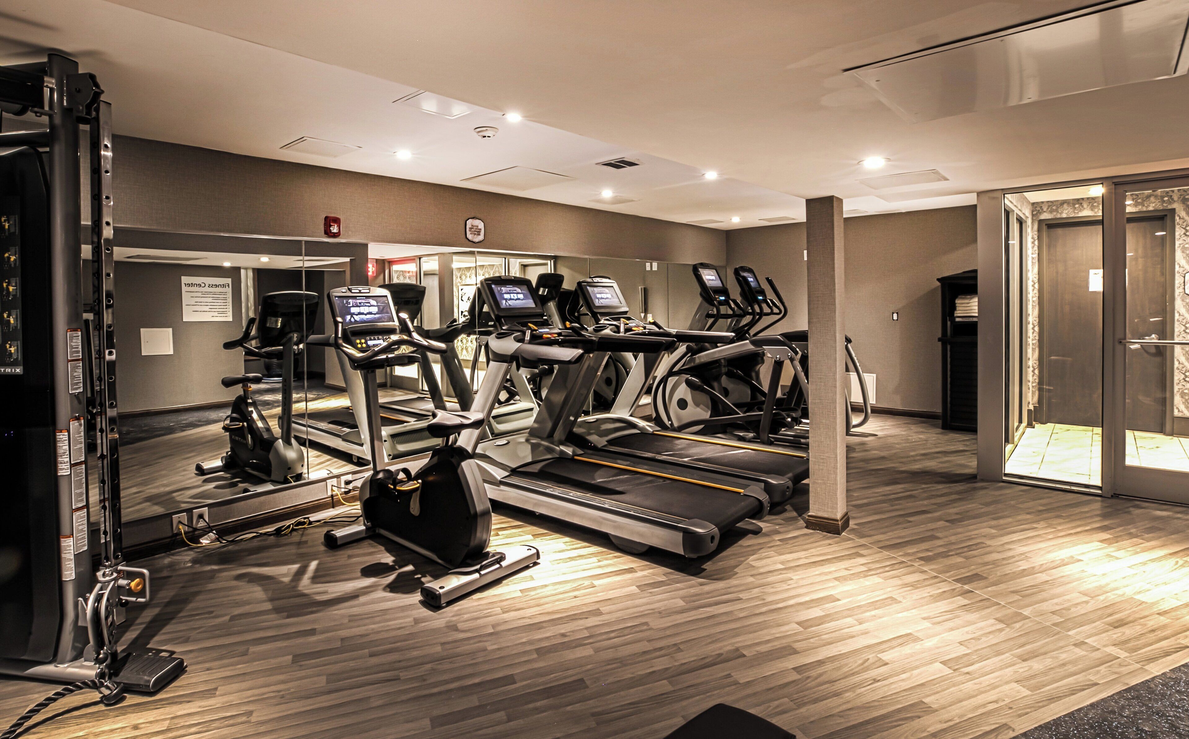 Un gimnasio con cintas de correr, elípticas y una máquina de remo.