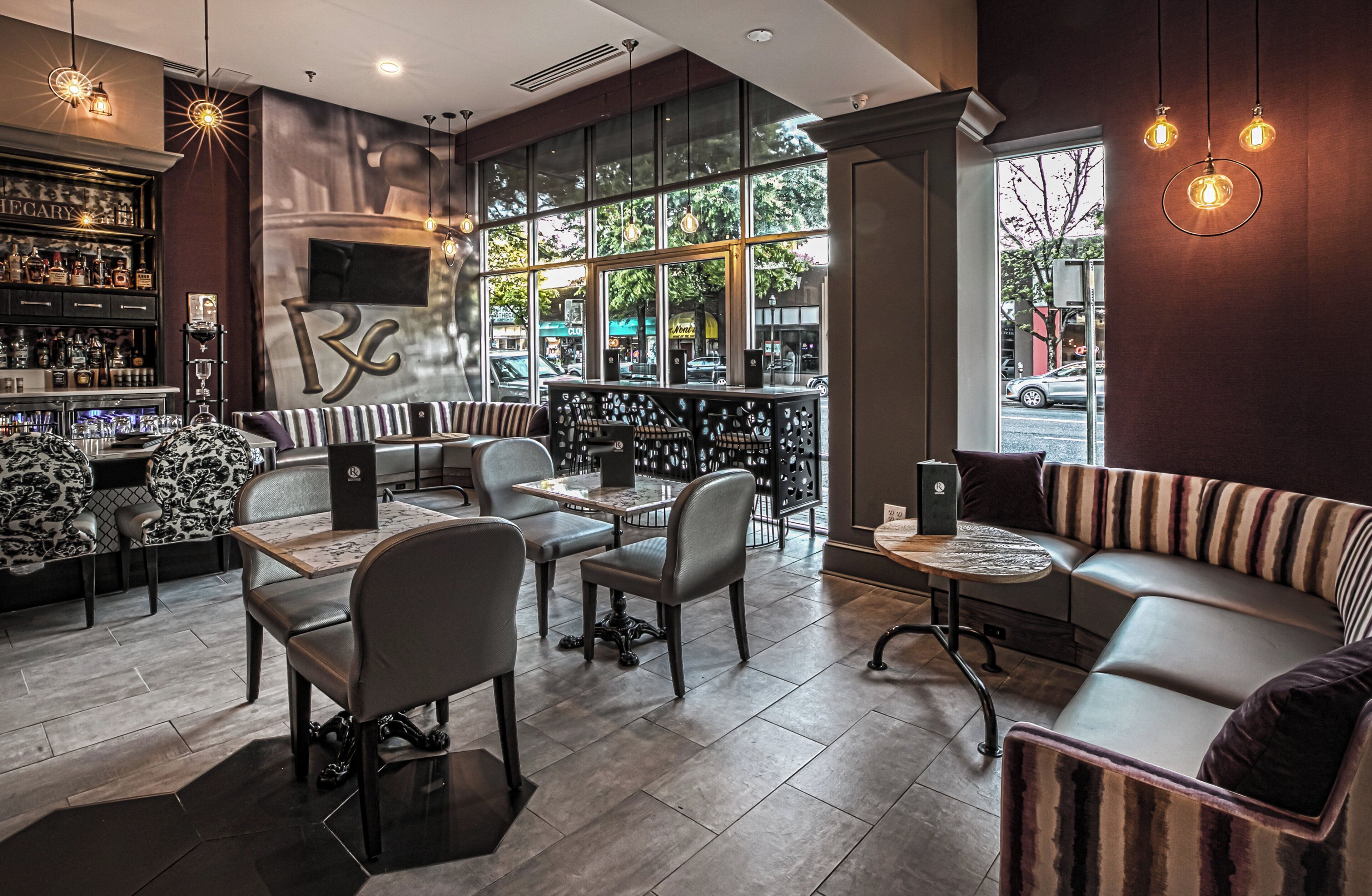 A modern bar area with seating, a large window, and a visible outdoor view.