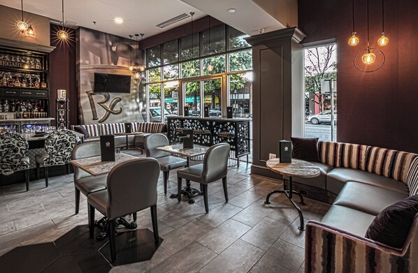 A modern bar area with seating, a large window, and a visible outdoor view.