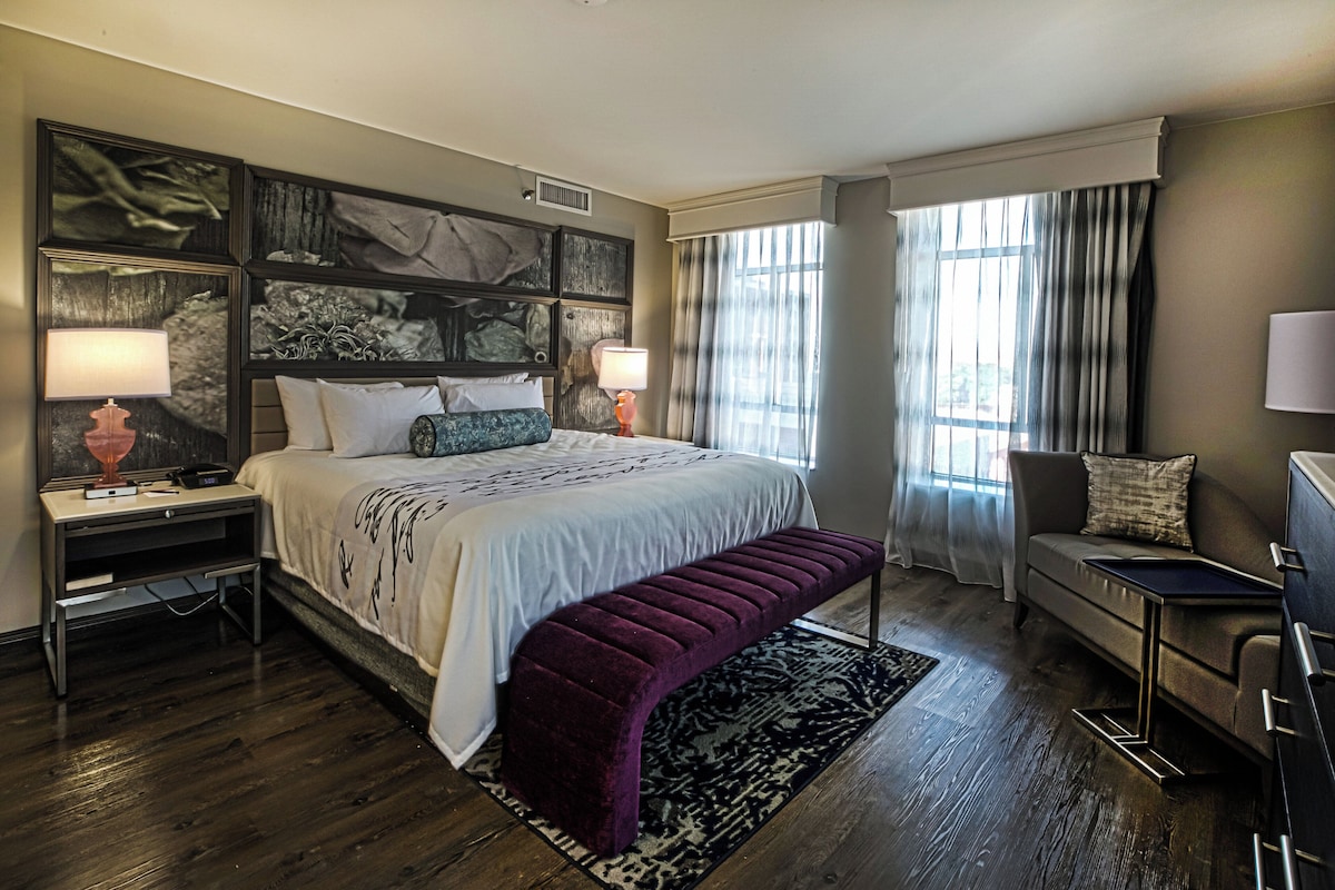 Une chambre d’hôtel avec un grand lit, un banc, un bureau et une chaise.