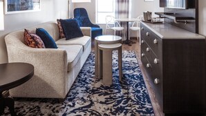 Una sala de estar moderna con un sofá, sillones, una mesa de centro, una televisión y un comedor con mesa y sillas.