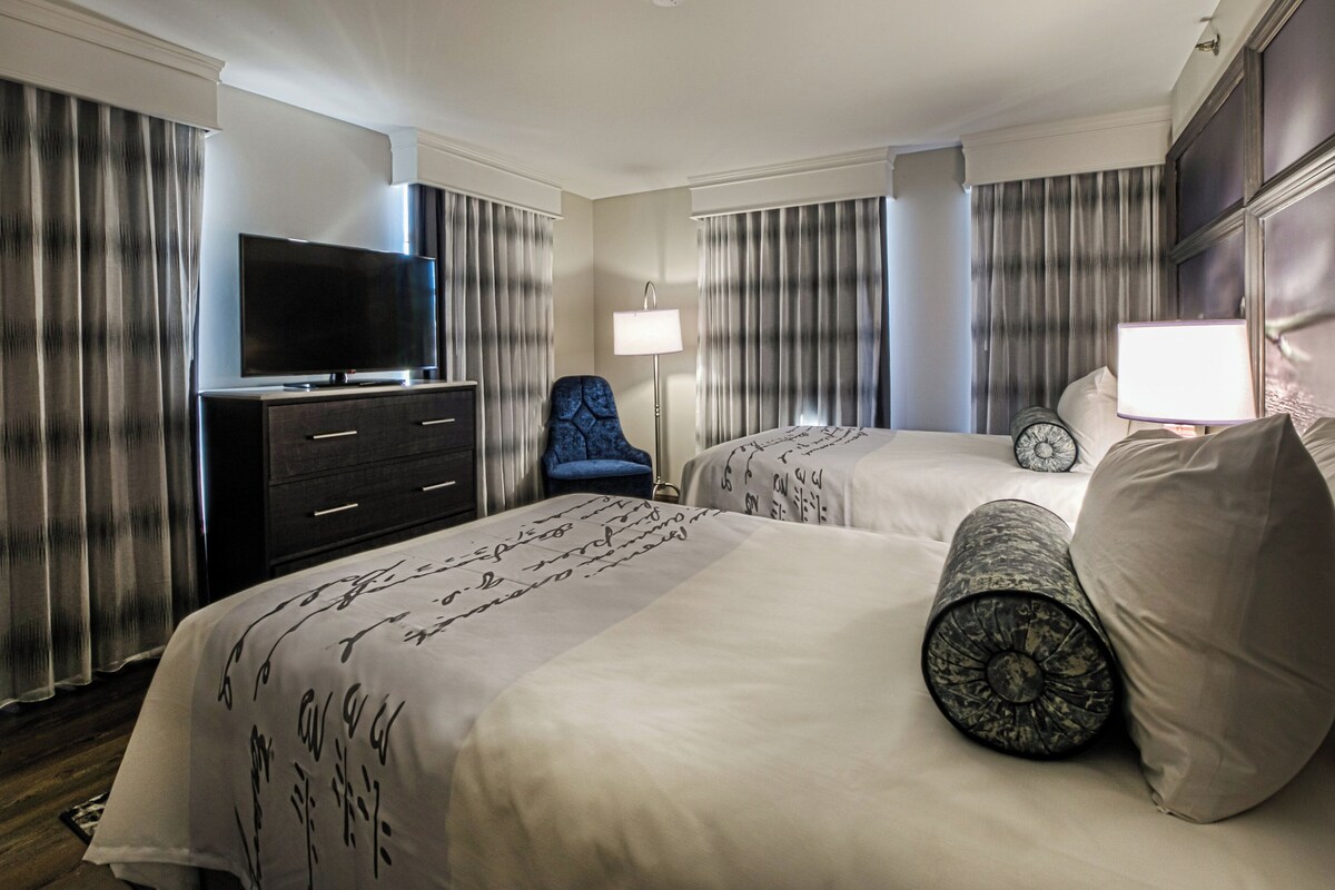 Une chambre d’hôtel avec deux lits, une télévision, un bureau et une chaise.