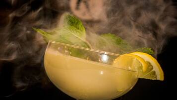 A cocktail with a lemon slice and mint leaves, surrounded by smoke.