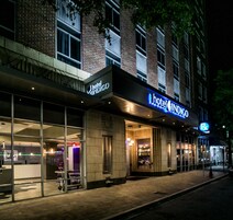 Un hotel con fachada moderna, amplias ventanas y un llamativo letrero que dice 'Hotel Indigo'.