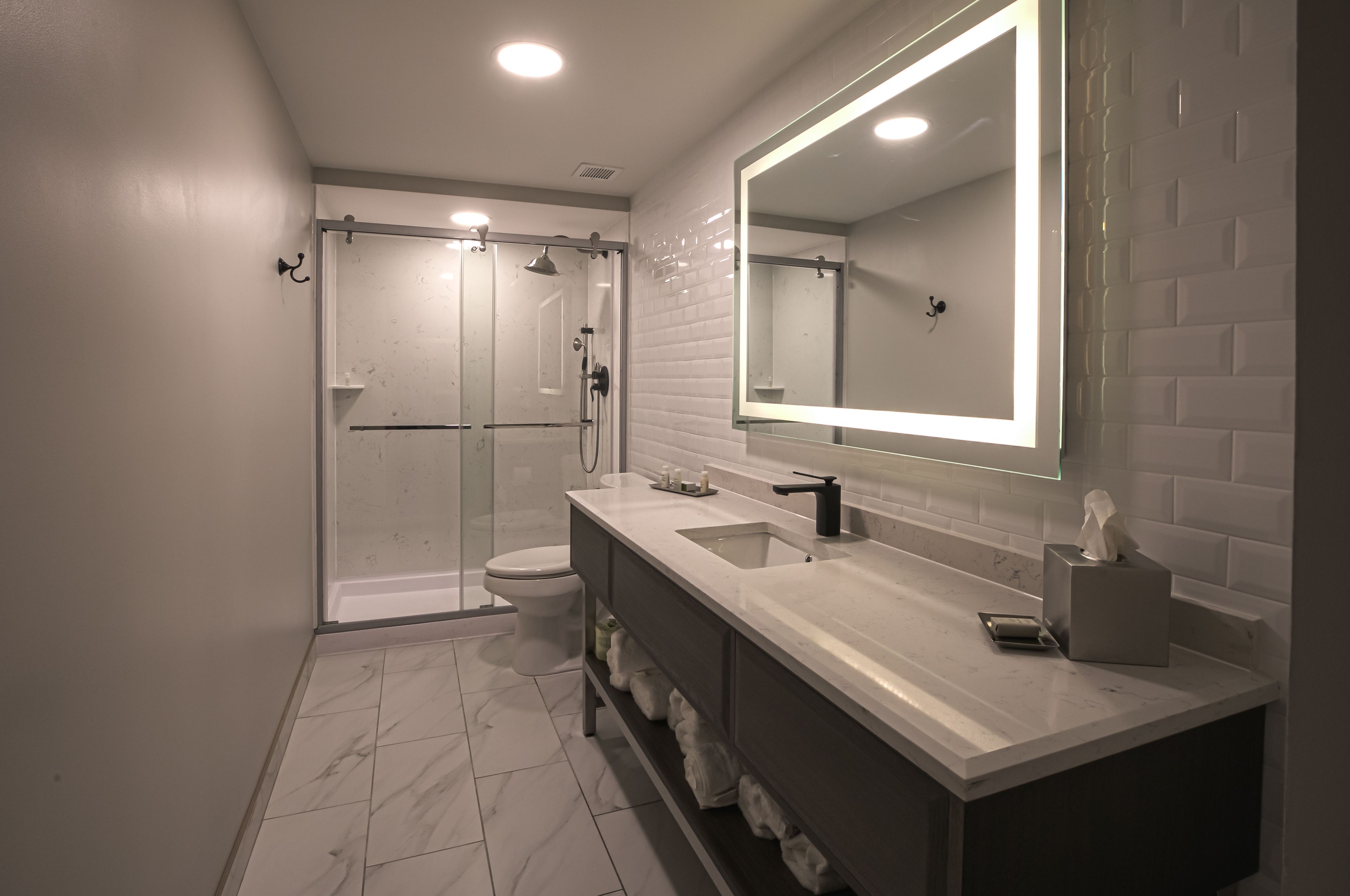 Un baño moderno con ducha a ras de suelo, inodoro, tocador con espejo y lavabo.