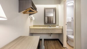 A compact bathroom with a wooden vanity, a sink, and a toilet. - Red Roof Inn Lansing West - MSU (Lansing)