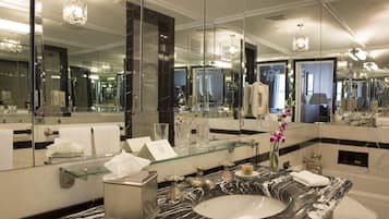 A luxurious bathroom with a marble sink, large mirrors, and a glass partition.