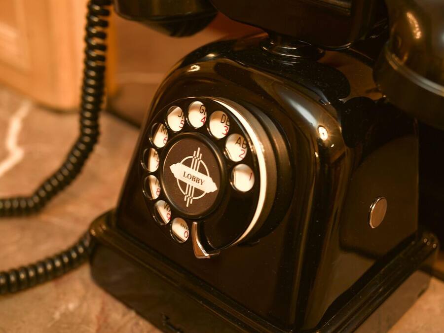 A vintage black rotary dial telephone with a 'Lobby' label on the dial.