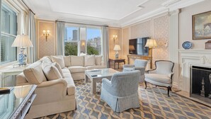 A spacious living room with a large sofa, armchairs, a coffee table, and a fireplace. - The Sherry Netherland (New York)