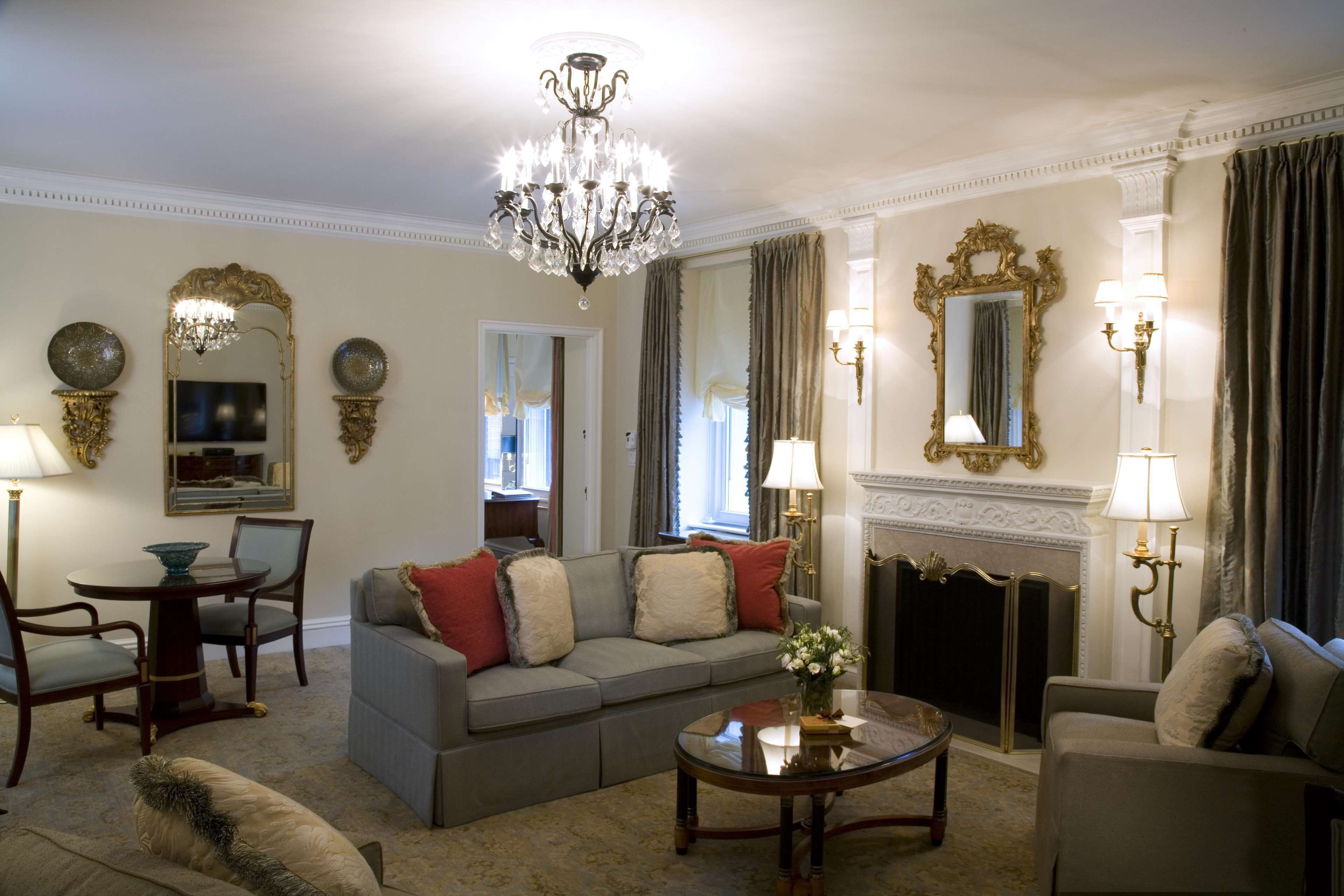 A well-furnished living room with a chandelier, sofas, a coffee table, and decorative mirrors.