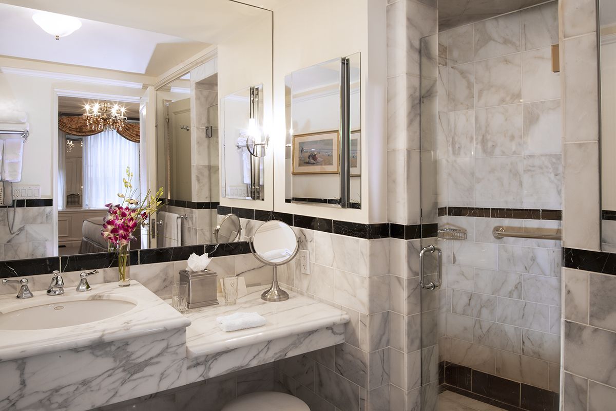 Une salle de bain moderne dotée d’un grand miroir, de deux lavabos, d’une zone douche et de toilettes.