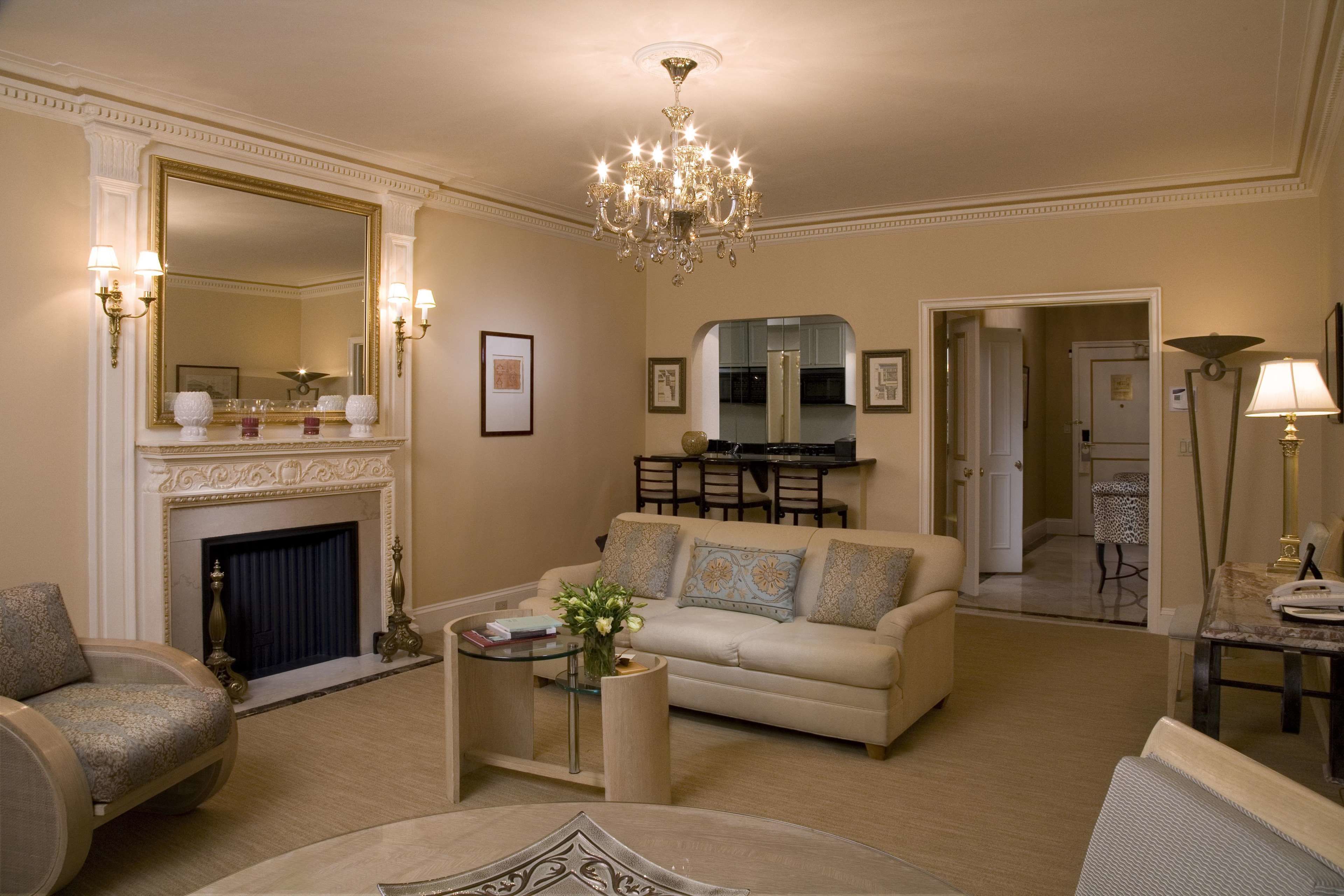 A spacious living room with a fireplace, a chandelier, and a dining area.