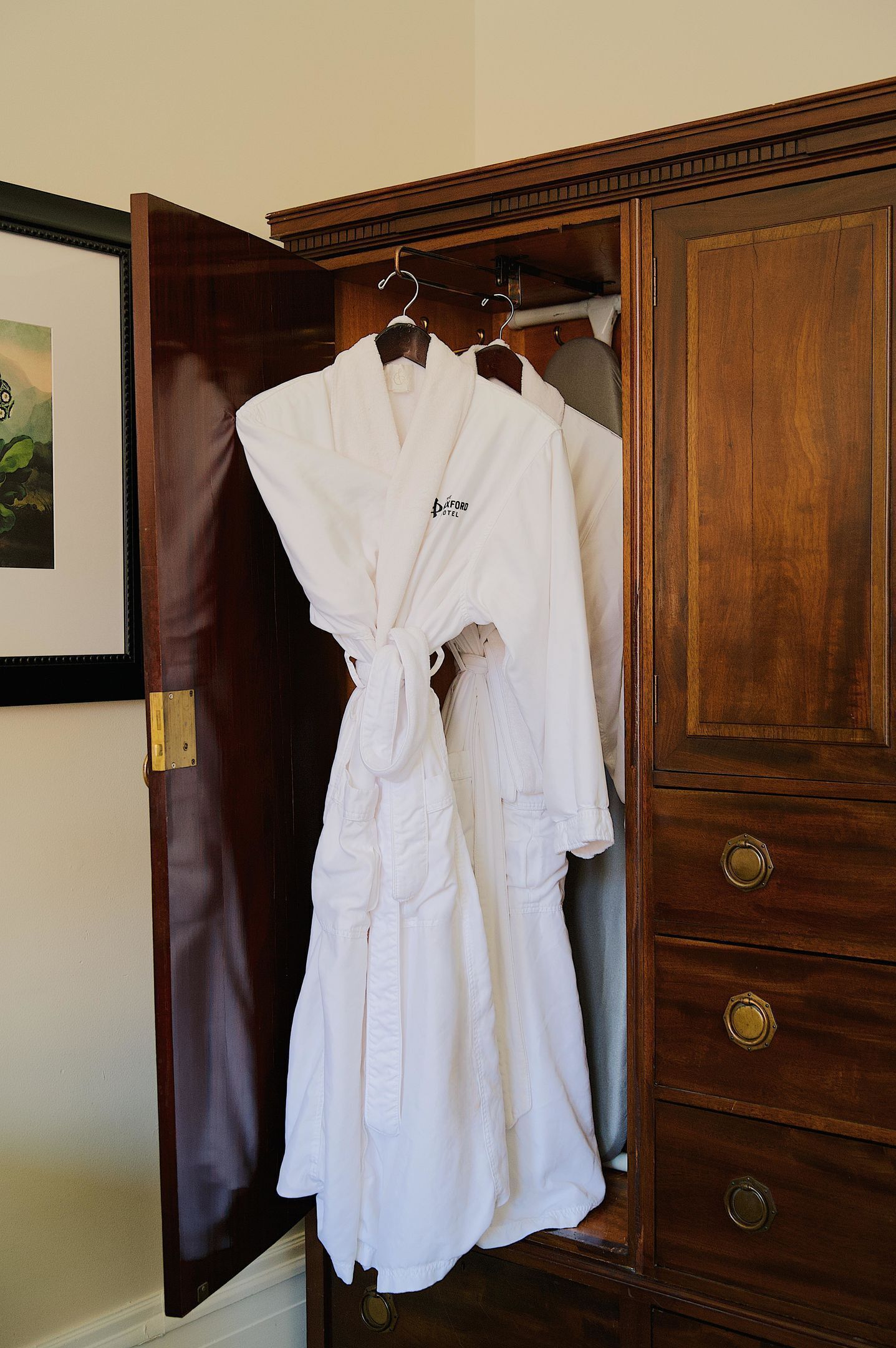 A wooden wardrobe with a robe hanging on a hanger.