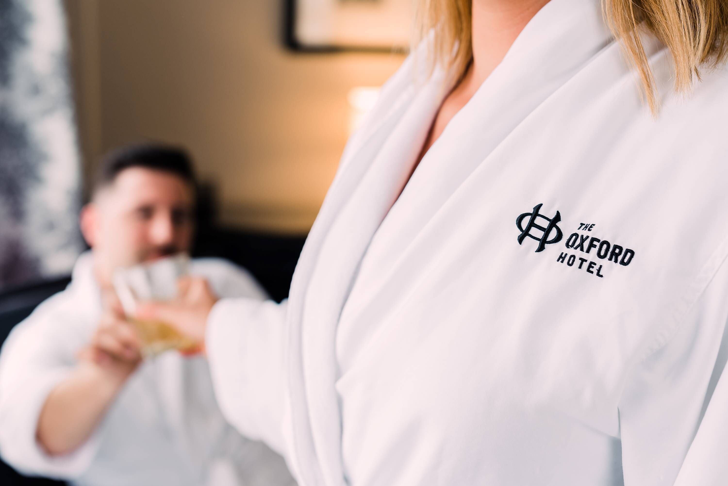 Una persona con una bata blanca y el logotipo de "The Oxford Hotel", lo que sugiere un entorno hotelero.