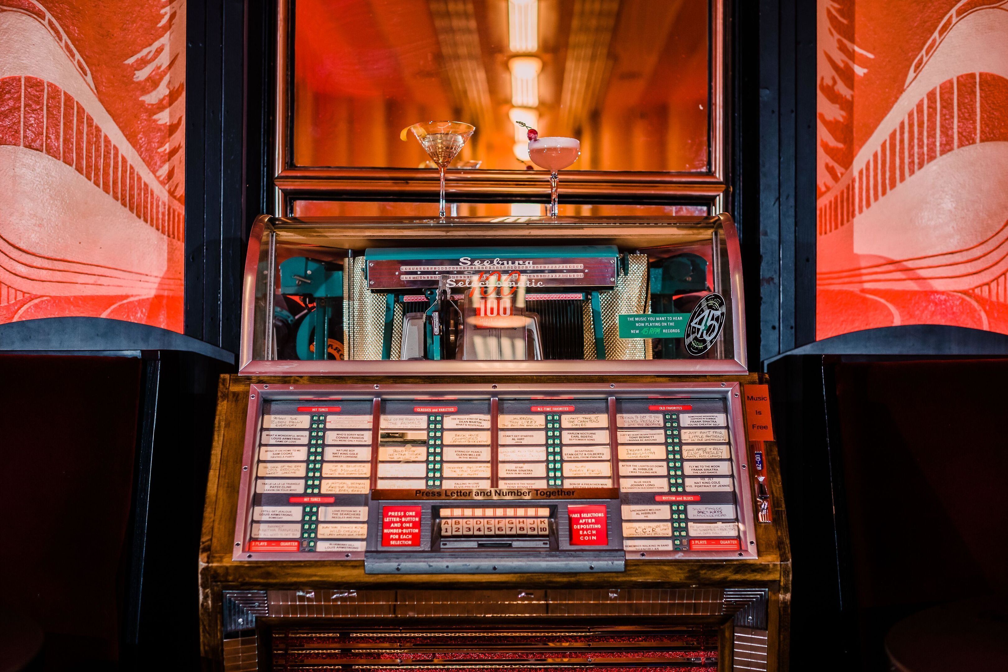 Um jukebox antigo com opções de bebidas e uma entrada para moedas.