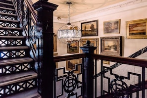 A grand staircase with ornate railings and a hanging light fixture. - The Oxford Hotel (Denver)
