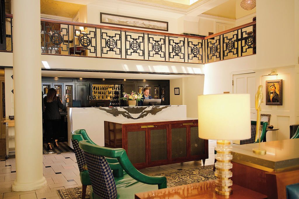 A lobby with a reception desk, a bar area, and a seating area with chairs.