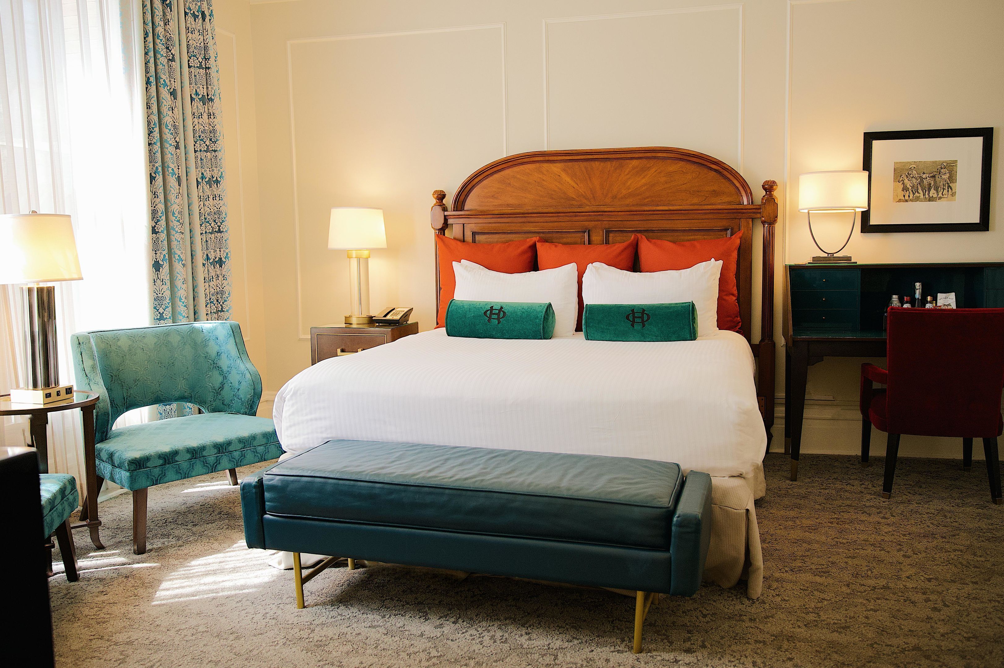 Una habitación de hotel con una cama grande, un escritorio, una silla y un banco.