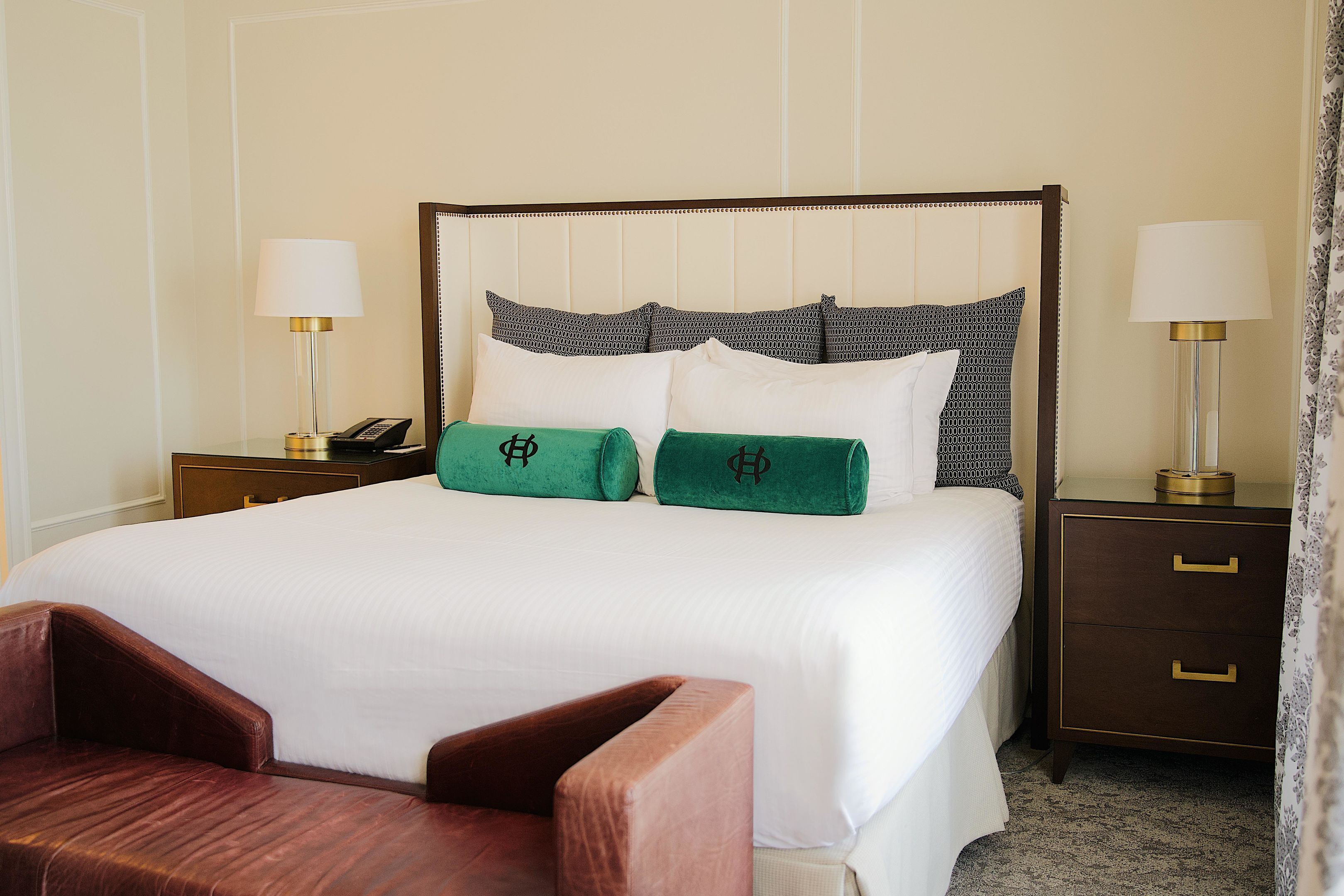 A hotel room with a large bed, two bedside tables, a nightstand, and a wooden chair.
