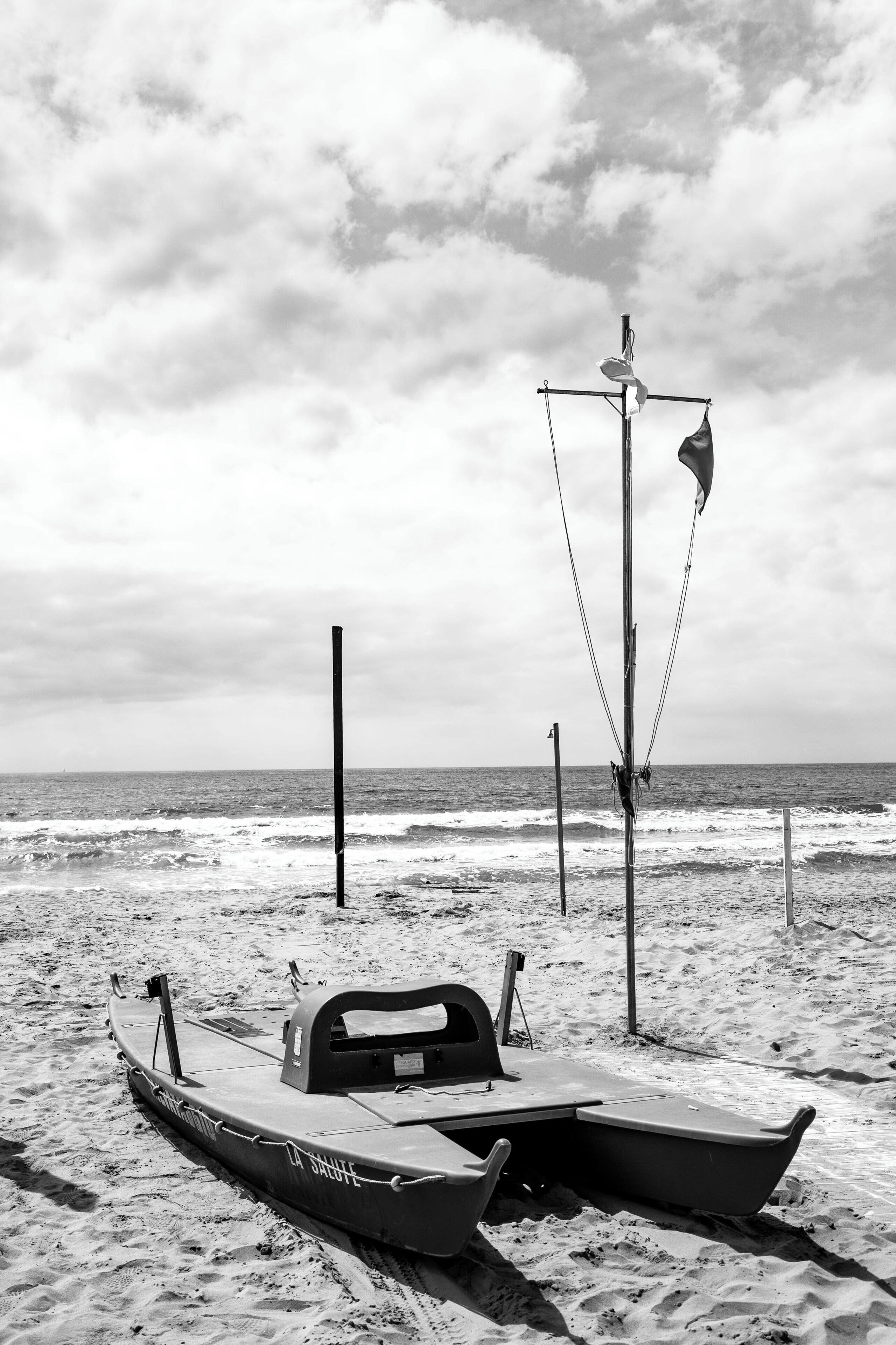 A boat on a sandy beach with a flagpole and a flag in the background.