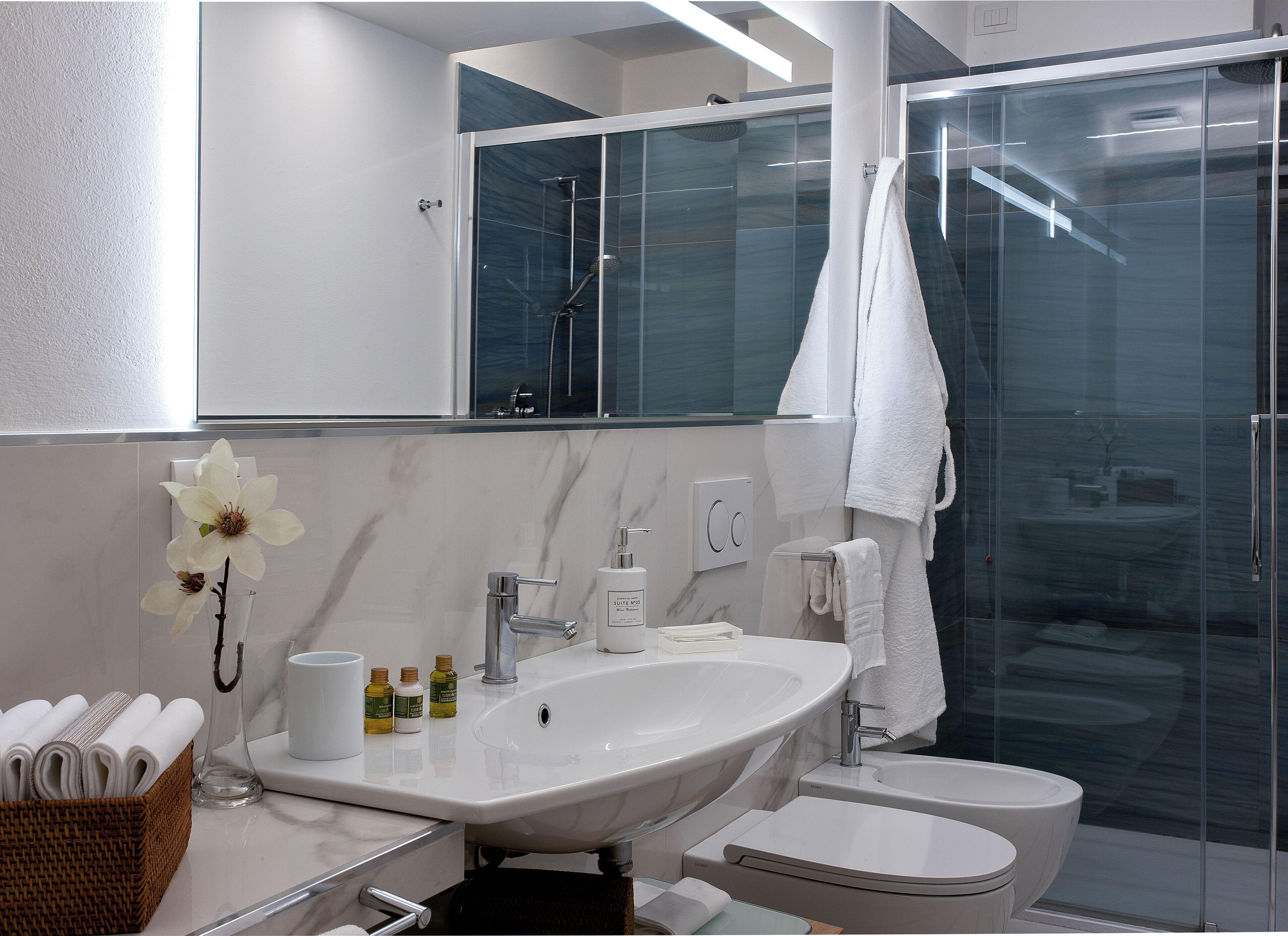 A modern bathroom with a large sink, toilet, and glass shower enclosure.