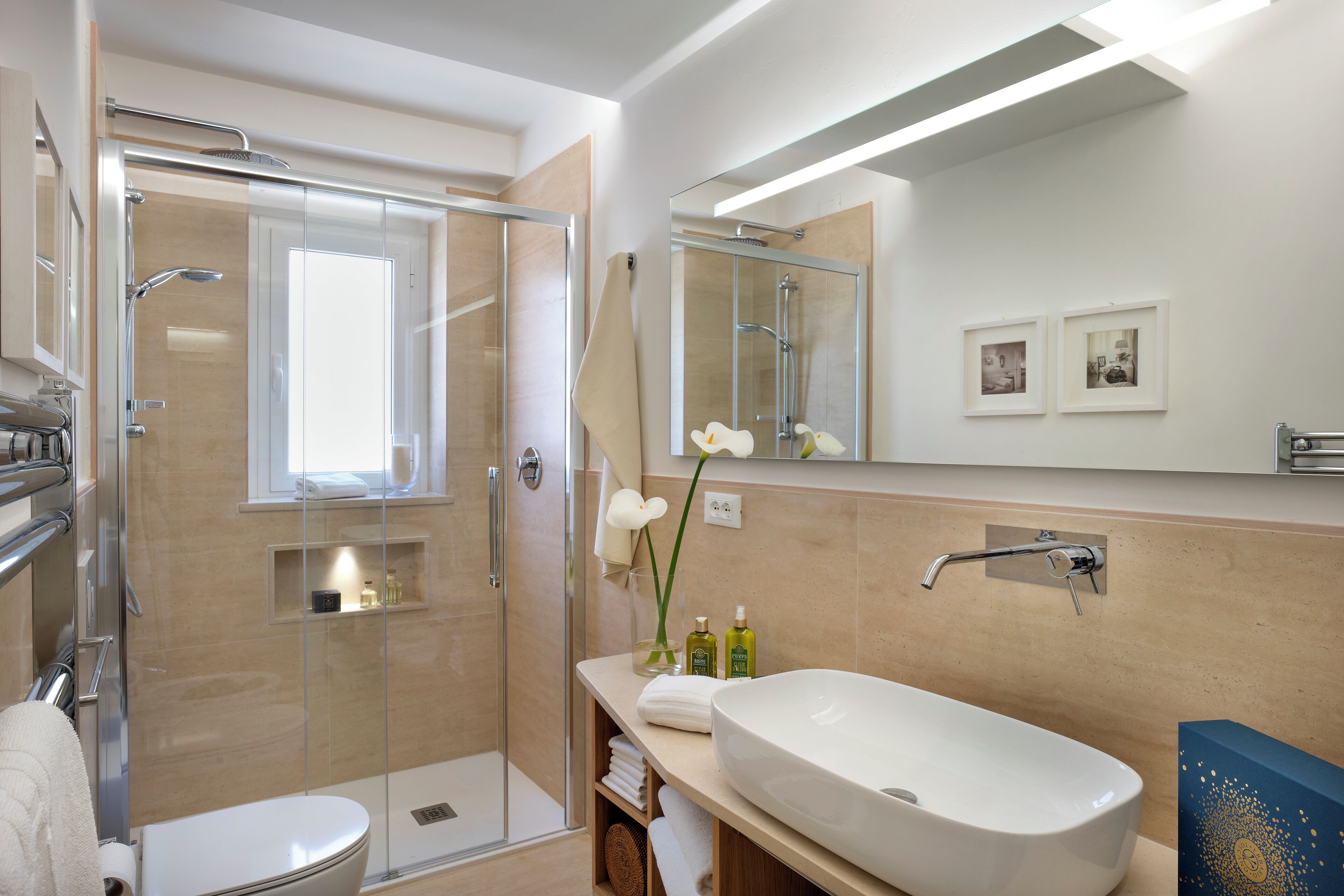 A modern bathroom with a glass shower enclosure, a white sink, and a large mirror.