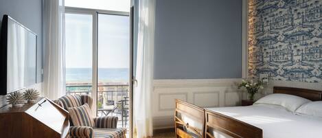A hotel room with a large window, a bed, a desk, and a chair.