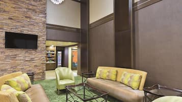 A lobby with a stone wall, leather sofas, a glass coffee table, and a chandelier.