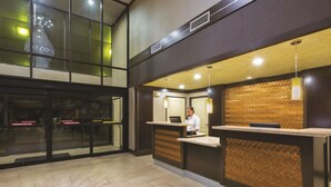 A reception area with a receptionist desk, a large chandelier, and a patterned wall. - La Quinta Inn by Wyndham Austin North (Austin)